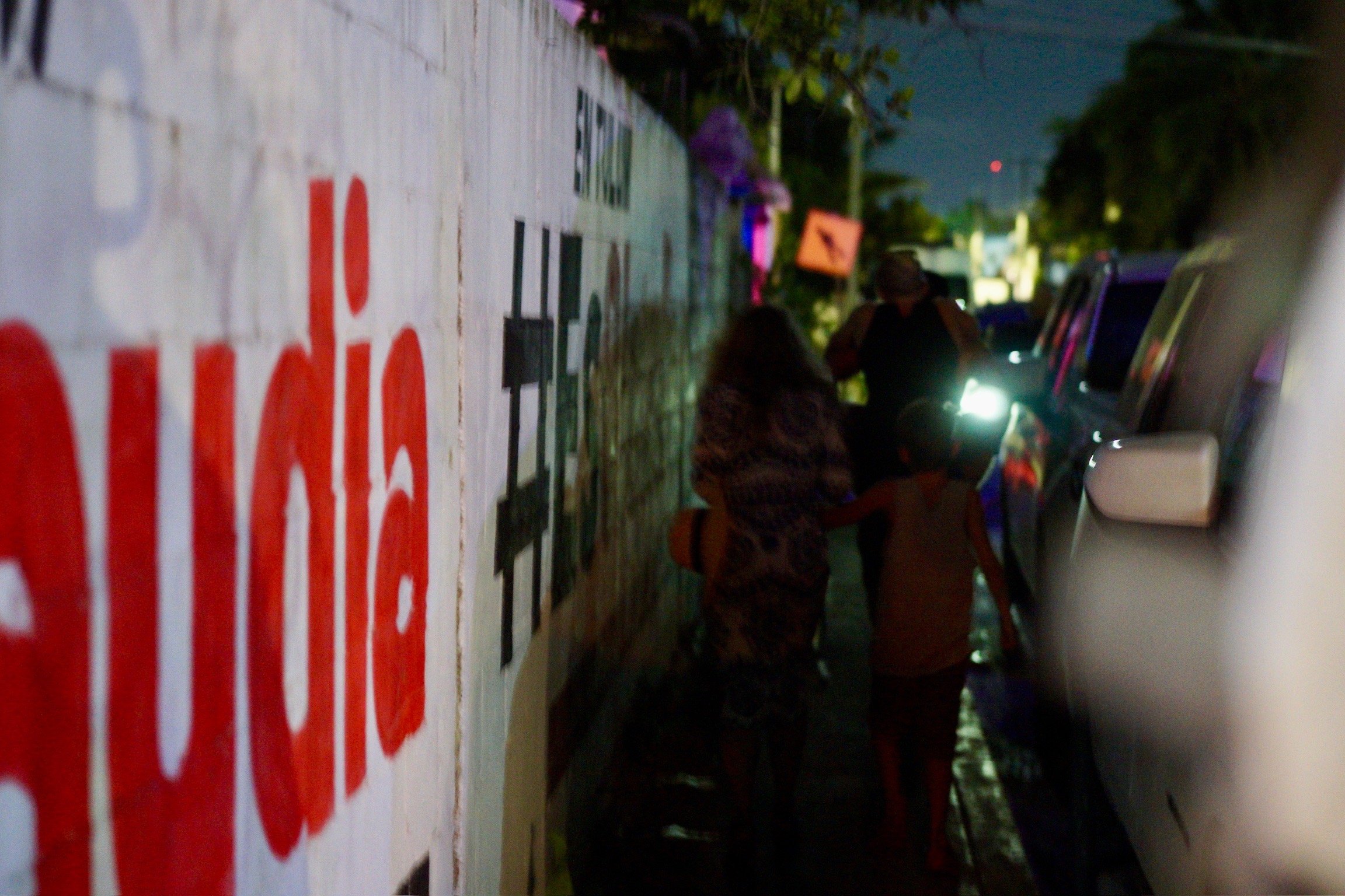 a family walking down a street in Tulum after dark